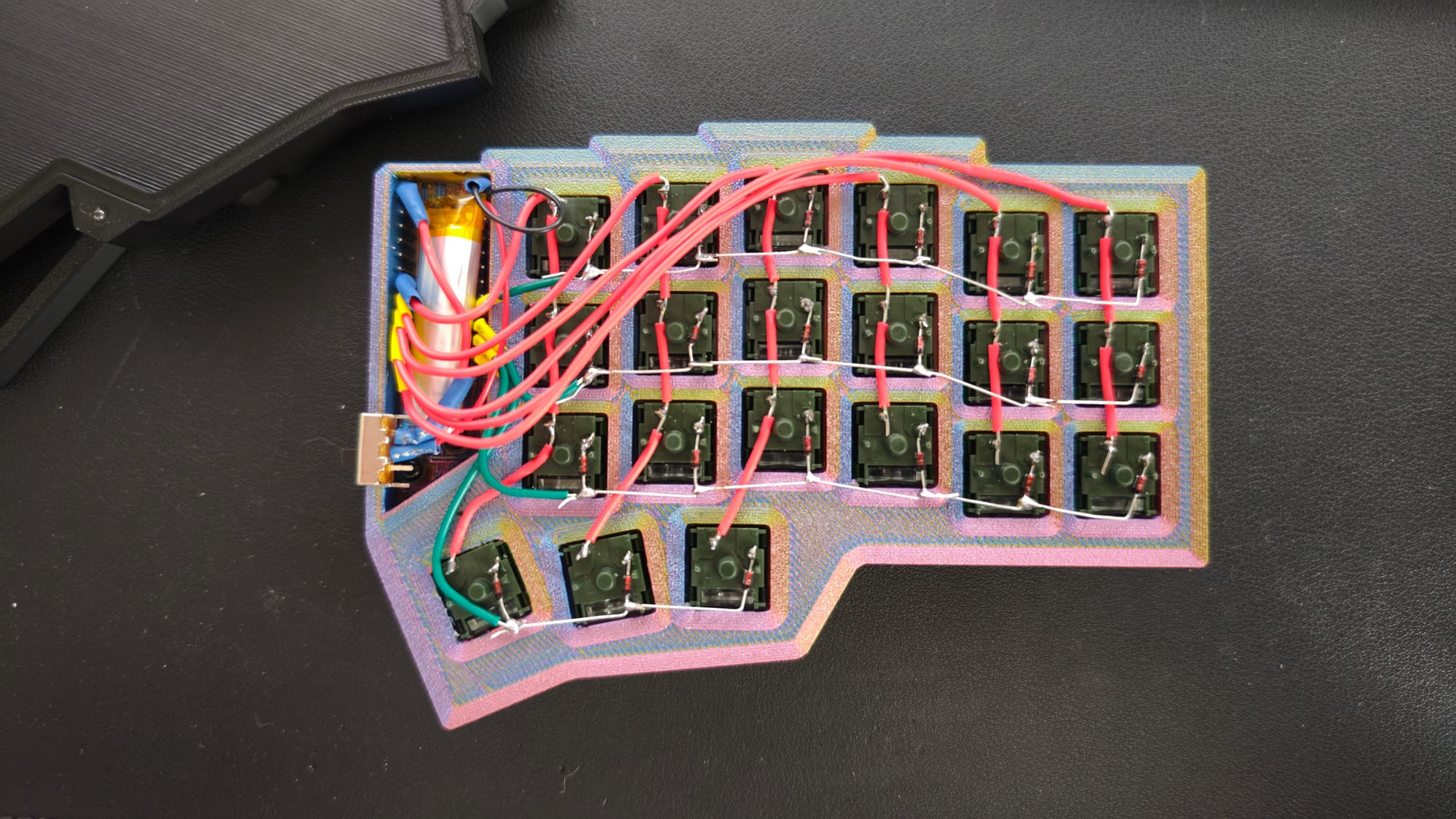 Underside of one half showing the handwired switch matrix — 1N4148 diodes bridging each switch, red and green solid-core wire running the rows and columns back to the nice!nano, with the battery seated top-left.